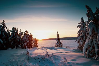 Sunset over frozen lake in winter clipart