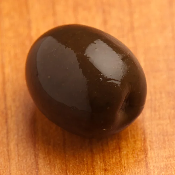 Einzelne Schwarze Oliven Auf Einer Holzoberfläche — Stockfoto