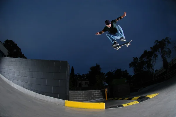 Скейтбордист прыгает с выступа — стоковое фото