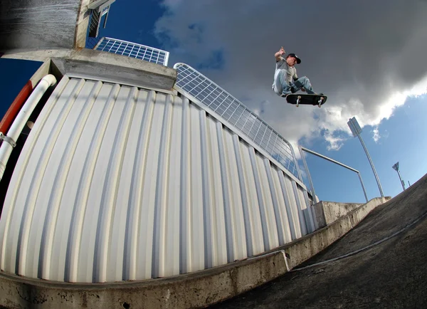 Skateboarder springen over de leuning Rechtenvrije Stockfoto's