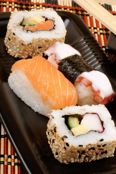 木の箸黒プレート上に添えて寿司の盛り合わせ — ストック写真