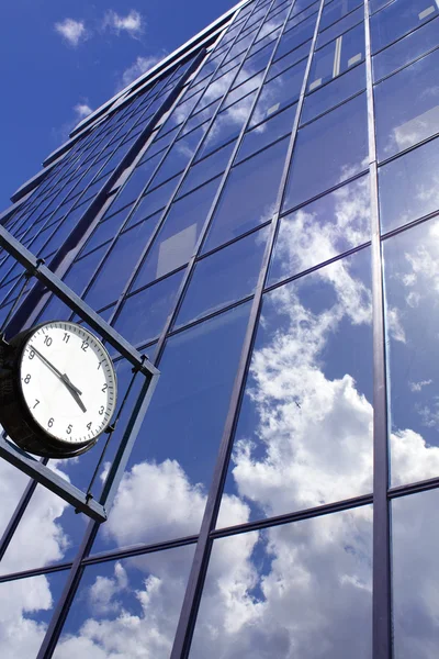 Uhr auf blauem Bürohaus-Hintergrund Stockbild