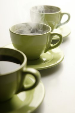 Three steaming mugs in a row in green colors clipart