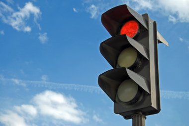 Red color on the traffic light with a beautiful blue sky in background clipart