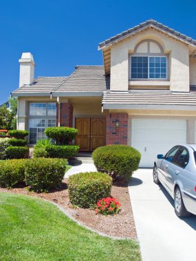 New American dream home with a beautiful blue sky in background and brand new car parked outside clipart