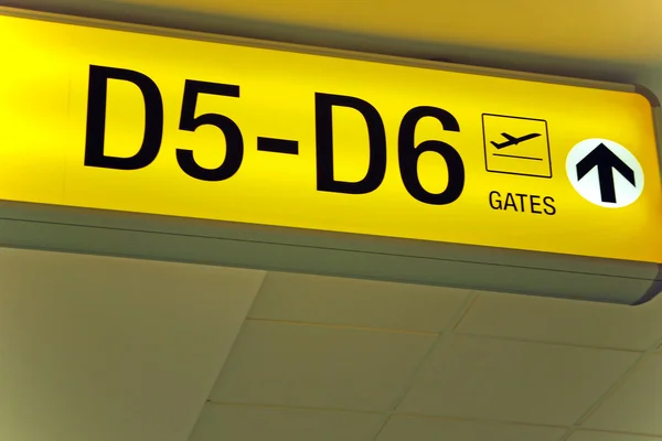 Vista detallada de la señal de salida del aeropuerto amarillo que muestra la dirección a las puertas — Foto de Stock