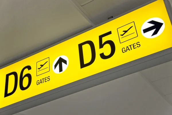Vista detallada de la señal de salida del aeropuerto amarillo que muestra la dirección a las puertas — Foto de Stock