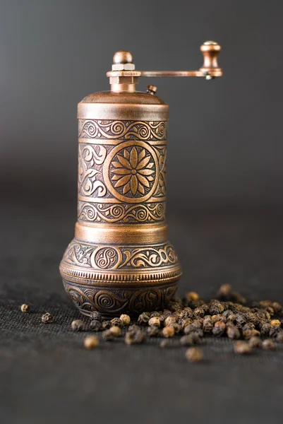 stock image Vintage still life with brass pepper mill standing on the grey background