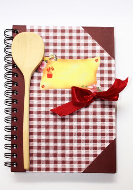 The book of recipes with a wooden spoon and a red bow. clipart