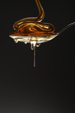 Golden honey wave spilling over the spoon clipart