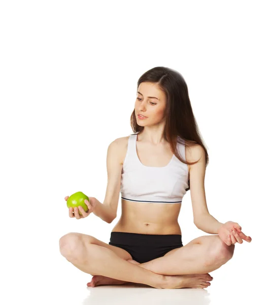 Girl in lotus position holds apple — Stock Photo, Image