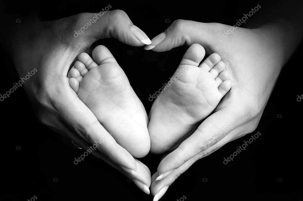 Baby"s feet in mom"s palms on black