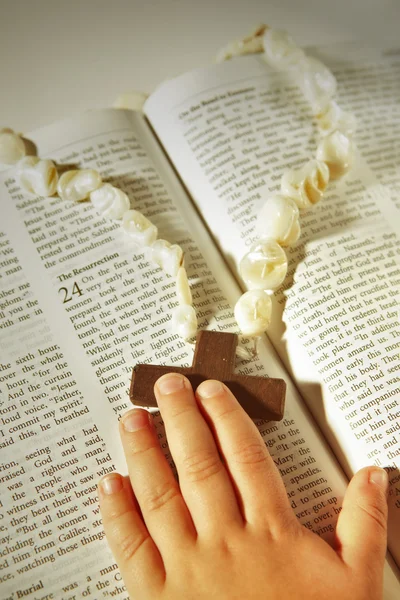 stock image Child hand and cross on the Bible .