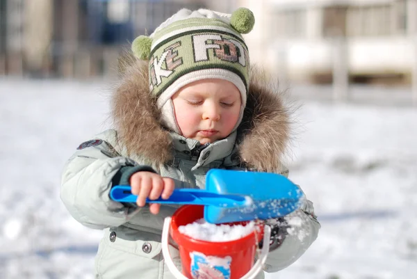 Kid samlar in snö Royaltyfria Stockfoton