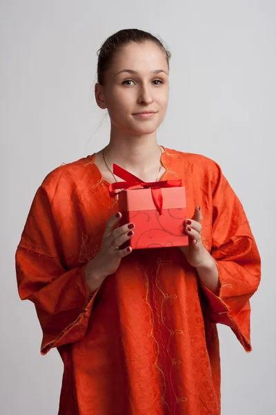 Дівчина в помаранчевій сукні з подарунком в руках — стокове фото
