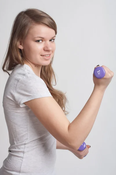 Girl with dumbbells in hand — Stock Photo, Image
