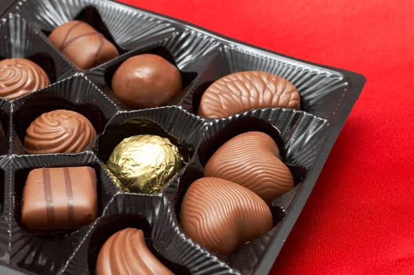 Valentim chocolates em caixa na seda vermelha — Fotografia de Stock