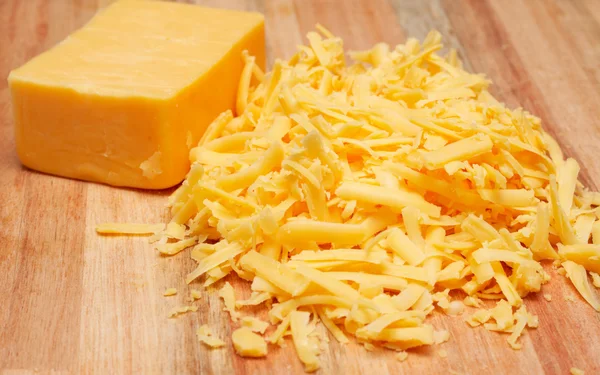 Sýr strouhaný čedar na dřevěné desce — Stock fotografie
