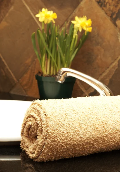 Zwinięte w ręcznik i kwiaty w łazience — Zdjęcie stockowe