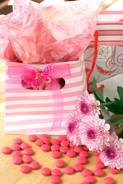 Два подарункові пакети з рожевими цукерками навколо — стокове фото
