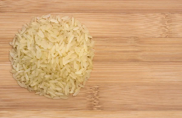 Heap of raw rice on a wooden table view from top with space for text