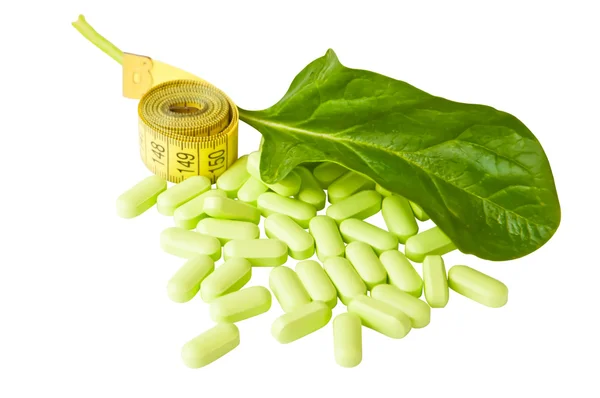 Measure tape, capsules and a green leaf — Stock Photo, Image