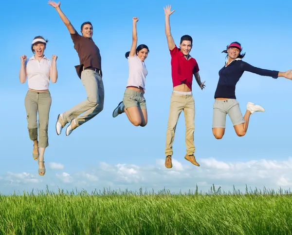 Прыжки молодых счастливых групп на лугу — стоковое фото