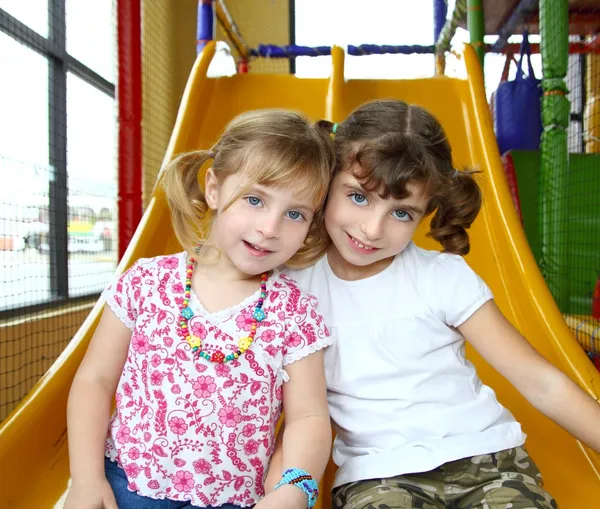 Filles sœurs amis sur aire de jeux jaune play slide — Photo