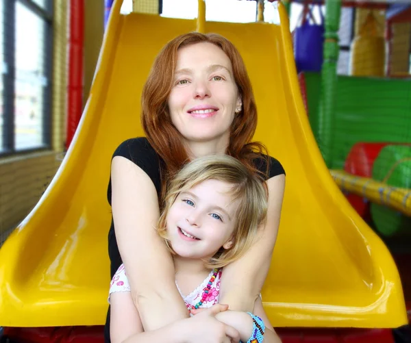 Daughter and mother together in playground slide — Stock Photo, Image