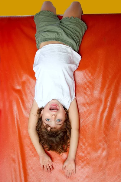 Dziewczynka na plac zabaw zjeżdżalnia śmiejąc się do góry nogami — Zdjęcie stockowe