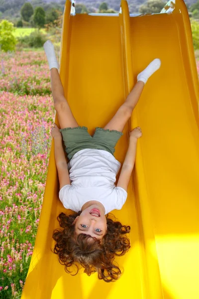 遊び場スライド ダウン逆さまのブルネットの少女 — ストック写真
