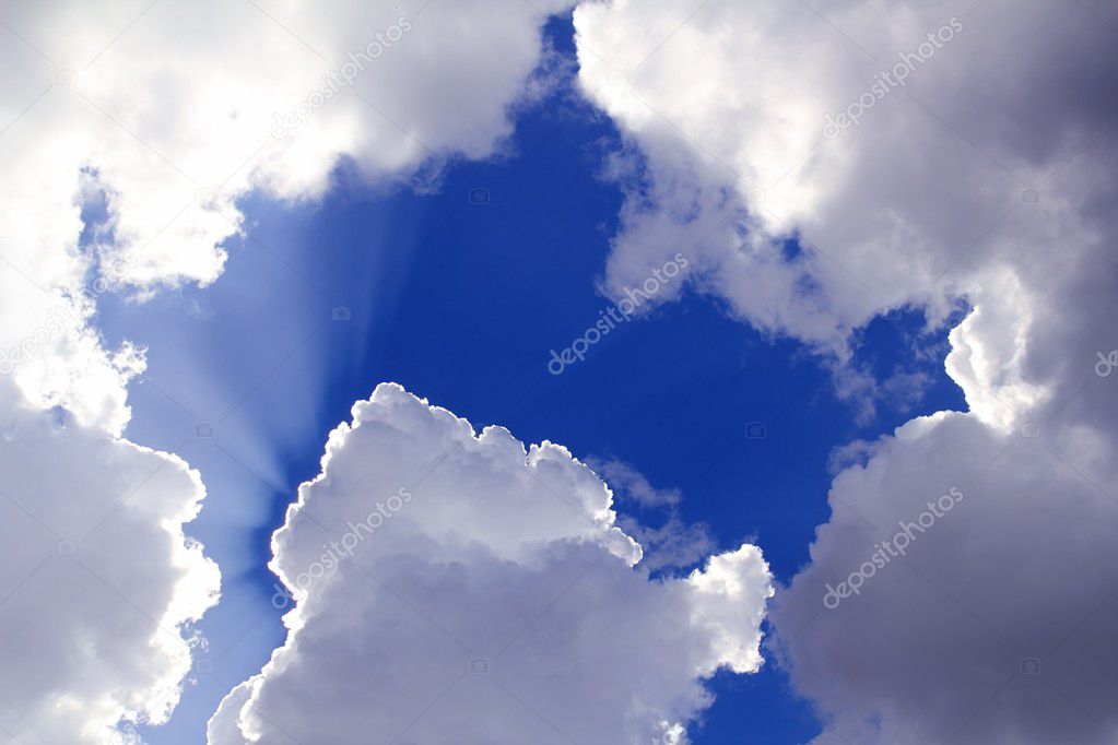 Beams from sun in blue sky gray clouds skyscape