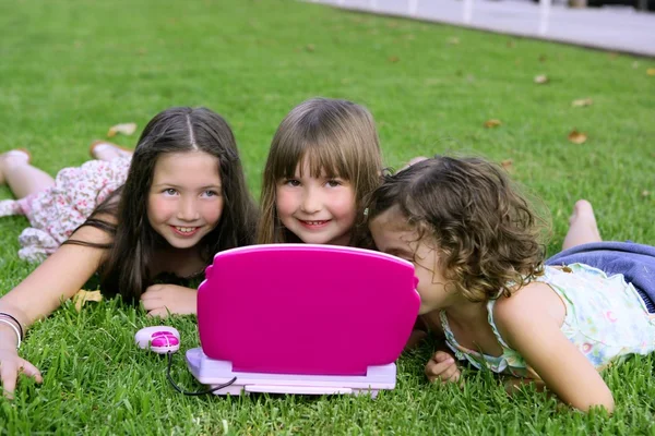 Tři malá holčička hraje s hračkou počítač v trávě — Stock fotografie
