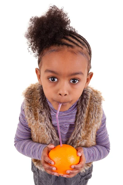 Маленькая черная девочка пьет апельсиновый сок с соломинкой — стоковое фото