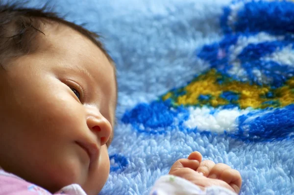 Den lille smukke baby ligger på et tæppe - Stock-foto