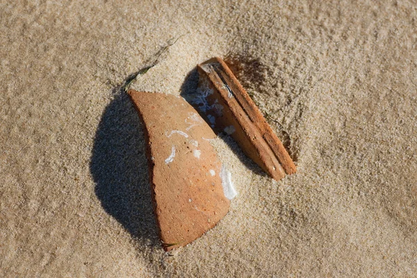 Разбитый керамический горшок на песке — стоковое фото