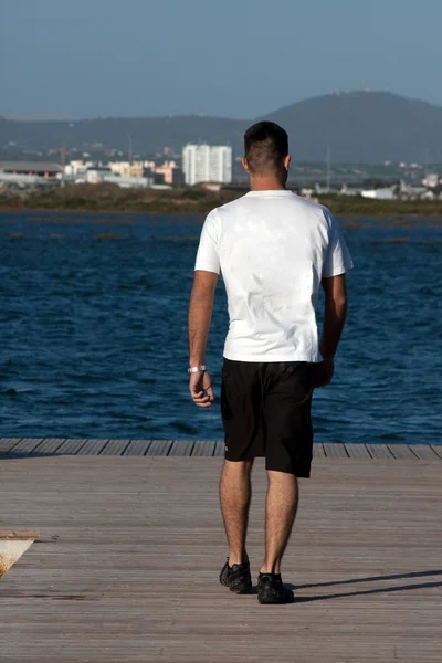 Jongeman loopt op pier — Stockfoto