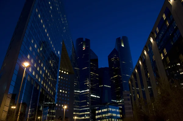 Skyline de rascacielos modernos con ventanas iluminadas y cielo oscuro durante —  Fotos de Stock