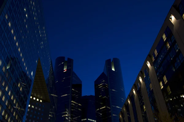 Skyline de arranha-céus modernos com janelas iluminadas e céu escuro durante — Fotografia de Stock