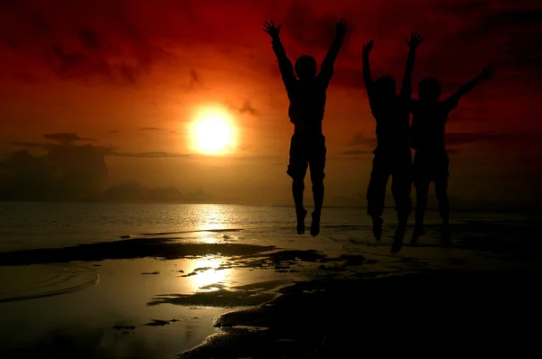 Силуэт троих прыгнул в восходящее солнце — стоковое фото