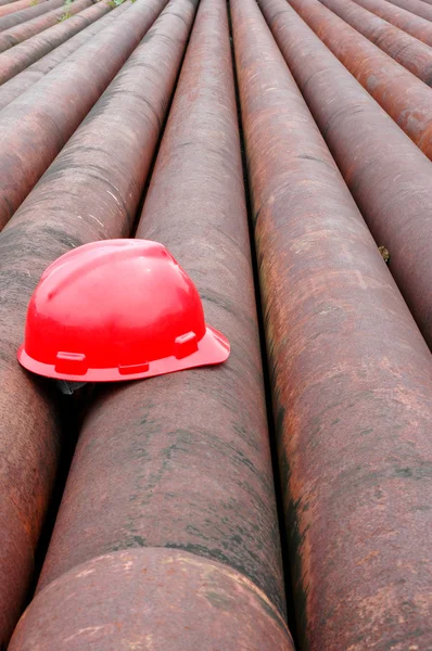 Óleo de mineiro capacete vermelho em tubo de ferro — Fotografia de Stock