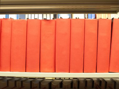 Stack of books in red binding on a library shelf clipart