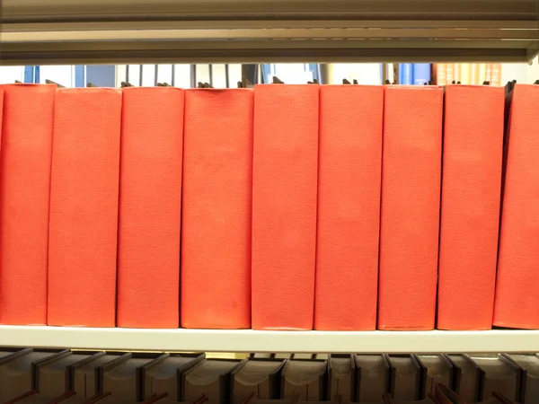 Stack of books in red binding on a library shelf