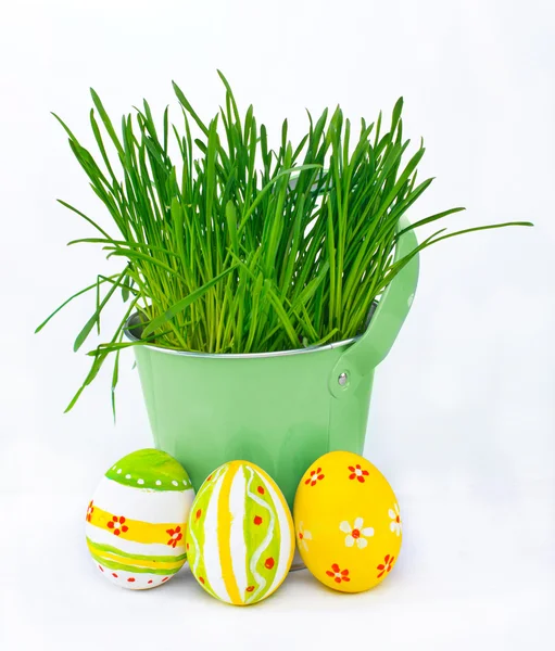 Colorful Easter eggs next to the bucket with the spring grass — Stock Photo, Image