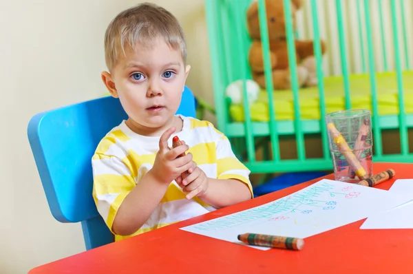 Ładny chłopiec rysuje kredkami w przedszkolu — Zdjęcie stockowe