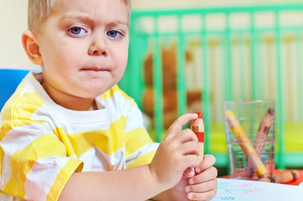 Маленький милий хлопчик малює з олівцями в дитячій — стокове фото