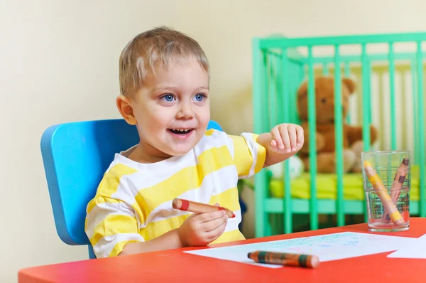Malý roztomilý chlapec kreslí pastelkami v dětském pokoji — Stock fotografie