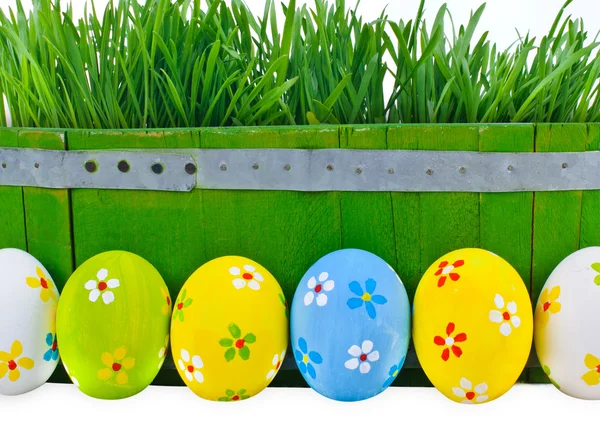 Easter eggs next to the bucket with the green grass — Stock Photo, Image