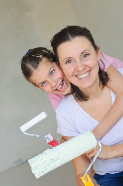 Мать и двойник краской стены с роликом — стоковое фото