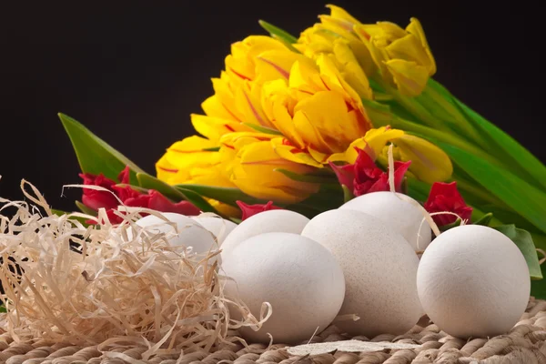 Ovos brancos e tulipas de primavera na bandeja de palha — Fotografia de Stock